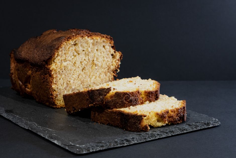 A beautiful loaf of golden-brown banana bread sliced on a wooden cutting board, showcasing a moist and tender interior without any nuts.