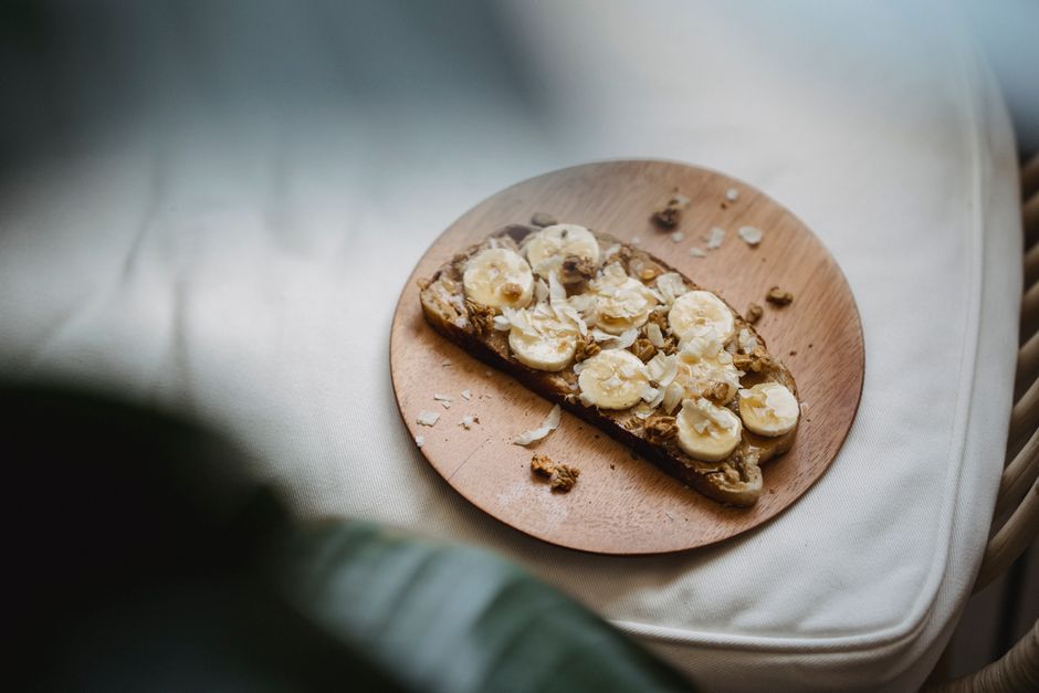 A beautiful slice of warm banana bread topped with a melting pat of butter on a rustic plate.