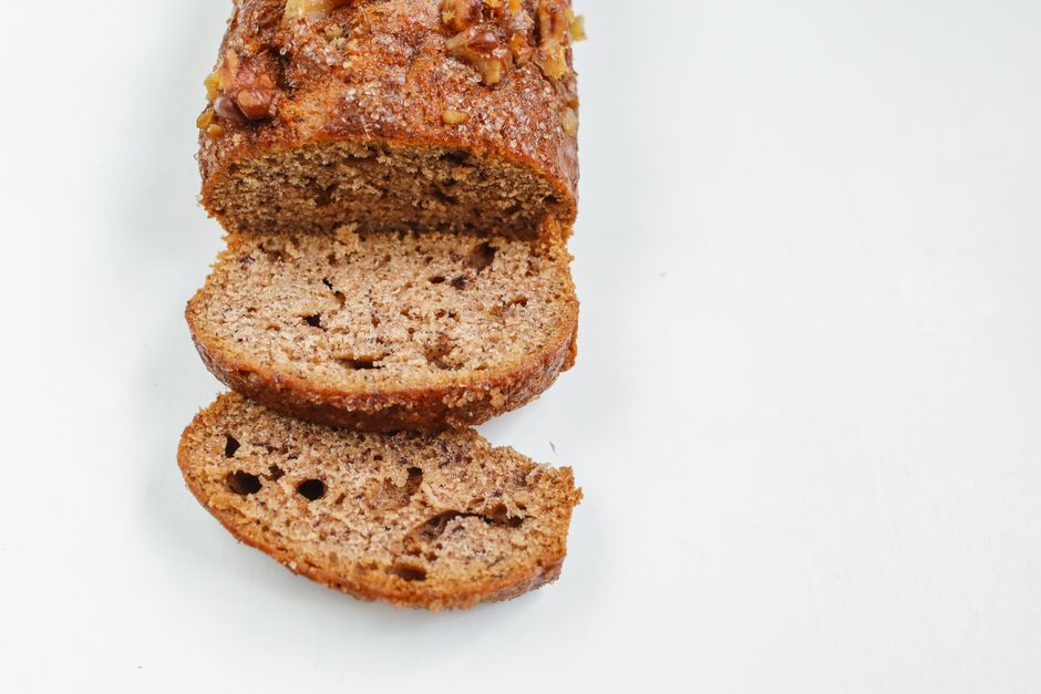 Authentic Jamaican Banana Bread Recipe: A Tropical Twist 1 A close-up of a sliced loaf of Jamaican banana bread, showing shredded coconut and a moist texture, set on a tropical leaf background