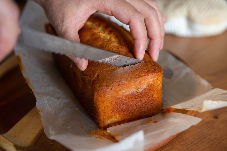 A close-up shot of a freshly sliced loaf of banana bread with cream cheese, showing its moist, tender crumb texture on a wooden cutting board