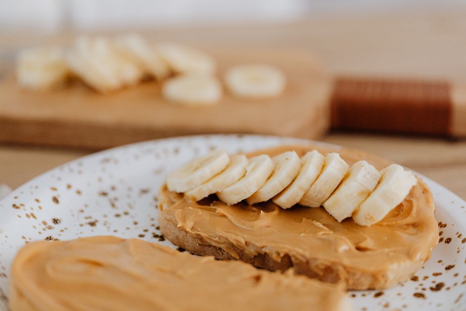 A close-up shot of a slice of gluten-free banana bread spread with a layer of creamy butter, showing the soft texture.