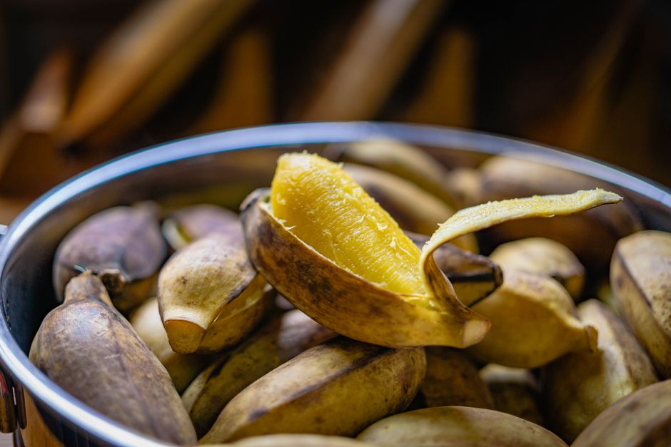 A close-up shot of mashing ripe bananas with a fork in a ceramic bowl