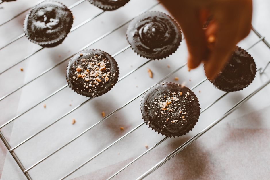 A display of different muffin variations on a cooling rack, including one topped with sliced bananas, one with walnuts, and one with a streusel crumb topping.