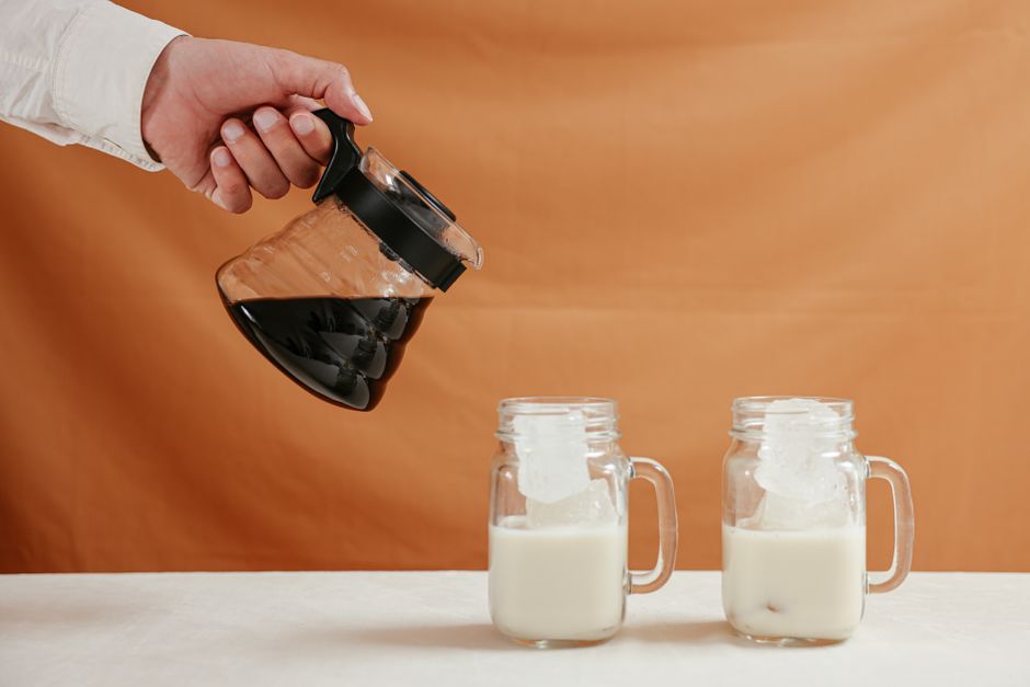 Homemade Banana Bread Coffee Syrup Recipe: Liquid Gold for Your Latte 3 A hand pouring the golden-brown banana bread syrup through a fine-mesh strainer into a clean glass mason jar