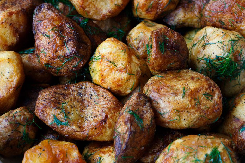 A rustic cutting board with freshly roasted, golden-brown herb potatoes, garnished with rosemary sprigs