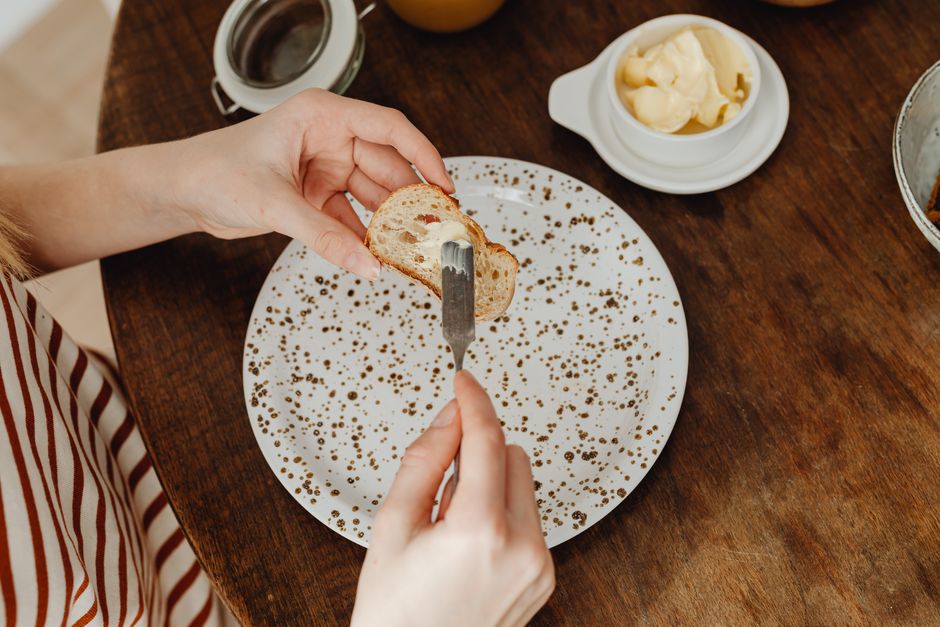 Super Moist Banana Bread with Mayonnaise Recipe 2 A slice of banana bread with mayonnaise spread with a thin layer of butter on a rustic plate.