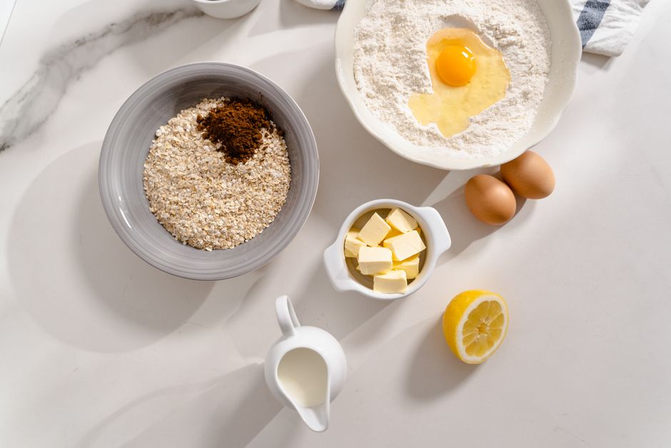 Ingredients for gluten-free banana bread laid out on a kitchen counter, including brown sugar, gluten-free flour, eggs, and spices.