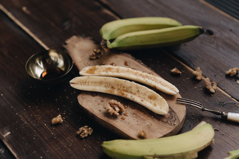Ultimate Banana Bread Recipe King Arthur Style: Moist & Fluffy 2 Slices of banana bread loaded with chocolate chips and walnuts, arranged on a rustic wooden board next to fresh bananas.