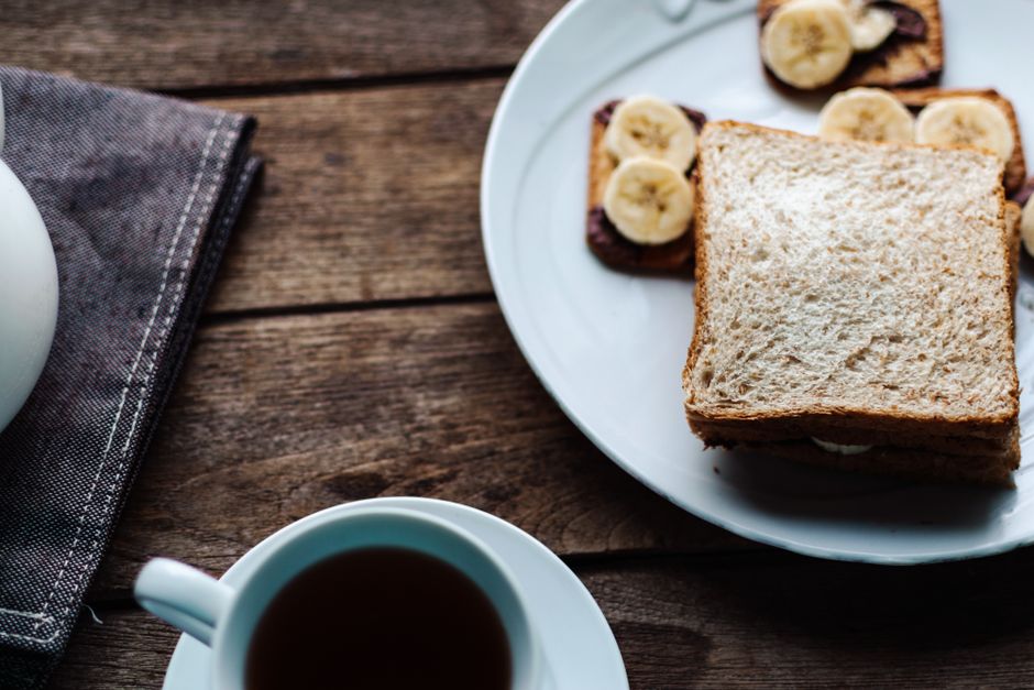 Moist Banana and Honey Bread Recipe - Naturally Sweetened 3 Slices of gluten-free banana honey bread served on a plate with fresh banana slices and a cup of tea nearby.